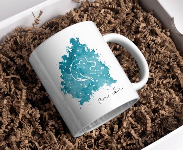 Weiße Tasse mit dem Sternzeichen-Symbol Löwe auf einem türkisfarbenen, sternenklaren Hintergrund und dem Namen ‚Annika‘. Ein personalisierbares Geschenk für Löwen und Astrologie-Fans.